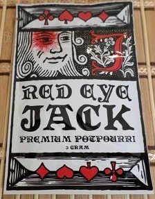 A beautifully lit Red Eye Jack Herbal Incense stick in an ornate holder, releasing fragrant smoke that fills the air with soothing aromas